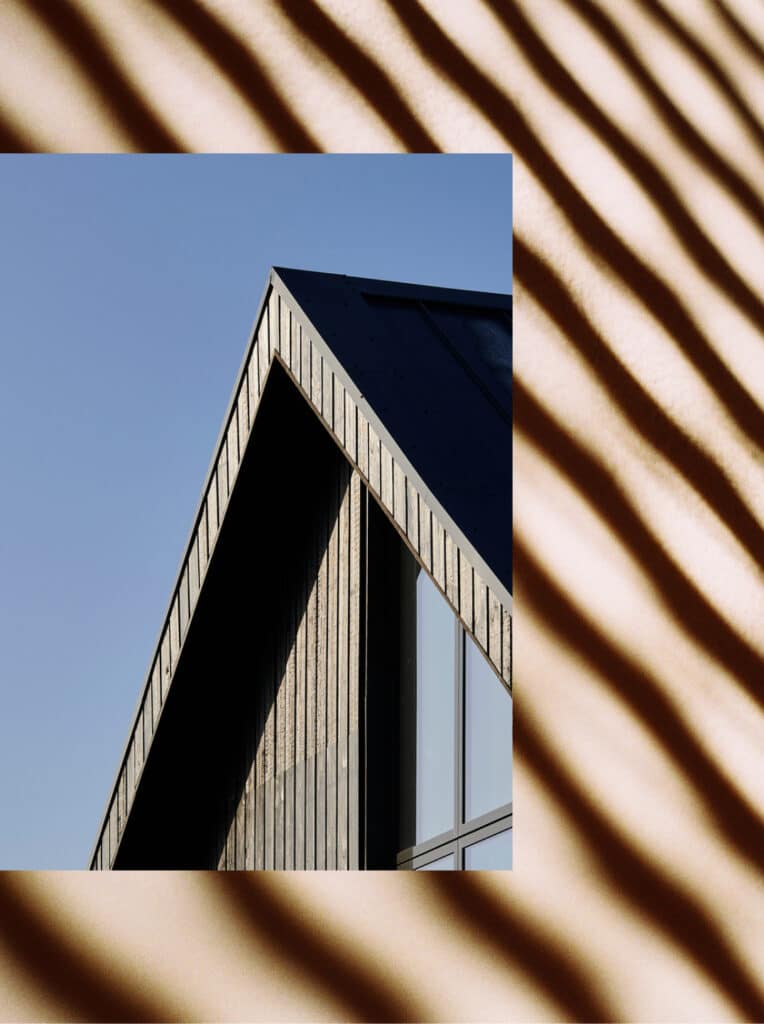 The peak of a roof on a house. The siding of the house is vertical wood